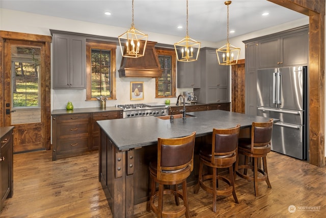 kitchen featuring pendant lighting, stainless steel appliances, a kitchen island with sink, and sink