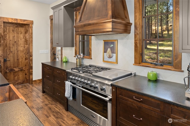 kitchen featuring decorative backsplash, premium range hood, range with two ovens, and dark hardwood / wood-style floors