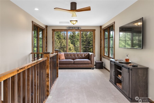 living area with light carpet and ceiling fan