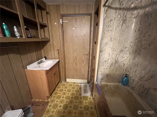 bathroom featuring vanity, wood walls, toilet, and a bath