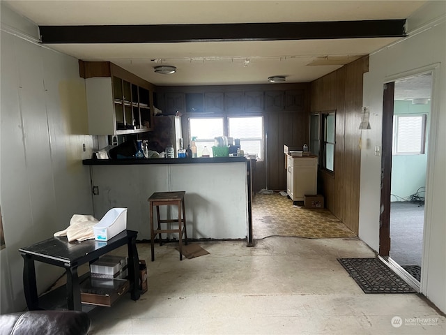 kitchen featuring kitchen peninsula, beam ceiling, and wooden walls