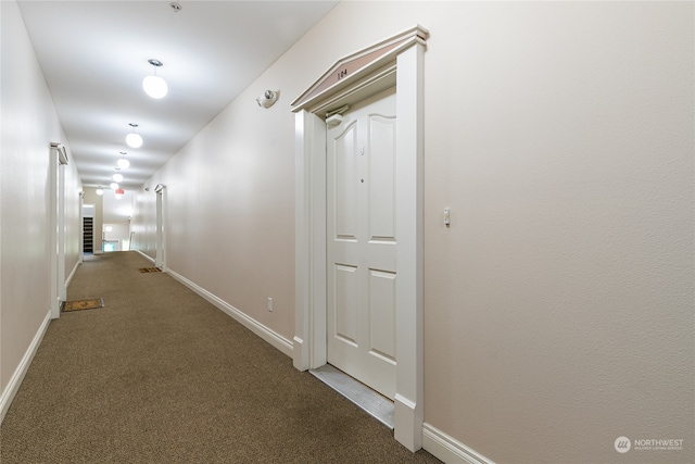 hall with dark colored carpet