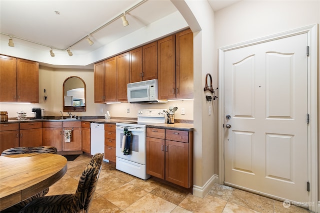 kitchen featuring white appliances, rail lighting, and sink