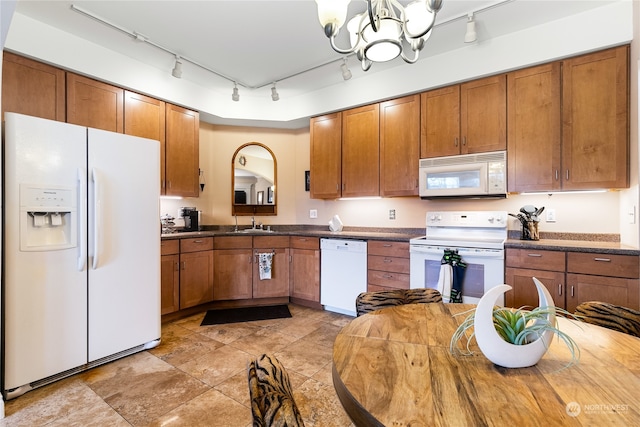 kitchen featuring sink, track lighting, white appliances, and an inviting chandelier