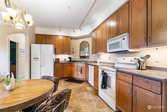 kitchen with track lighting, white appliances, sink, decorative light fixtures, and an inviting chandelier