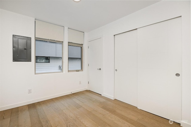 unfurnished bedroom with electric panel, a closet, and light wood-type flooring