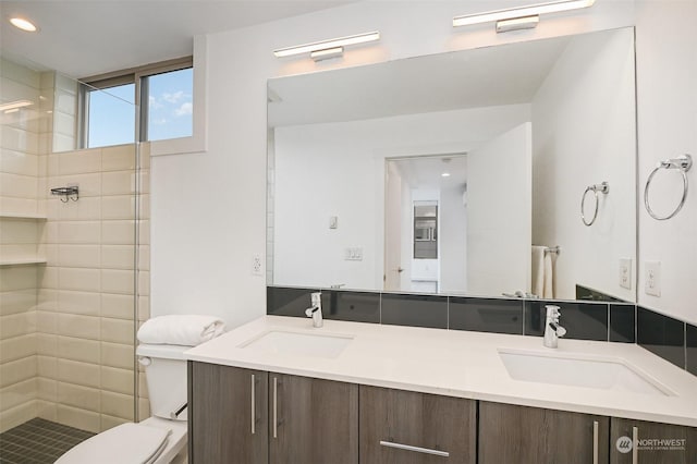 bathroom featuring vanity, toilet, and a tile shower