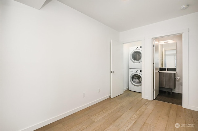 laundry room featuring stacked washer and dryer and light hardwood / wood-style flooring