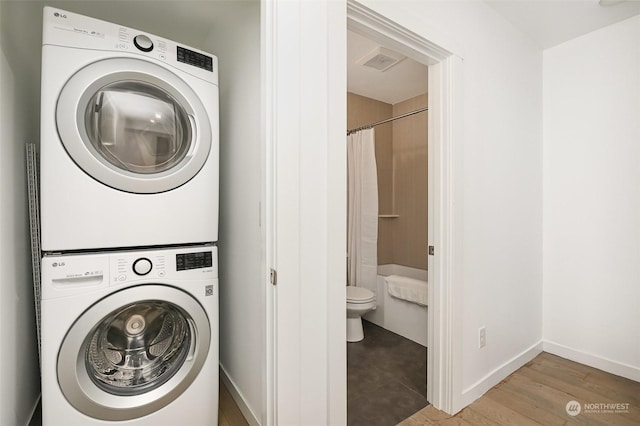 washroom with hardwood / wood-style floors and stacked washer and clothes dryer