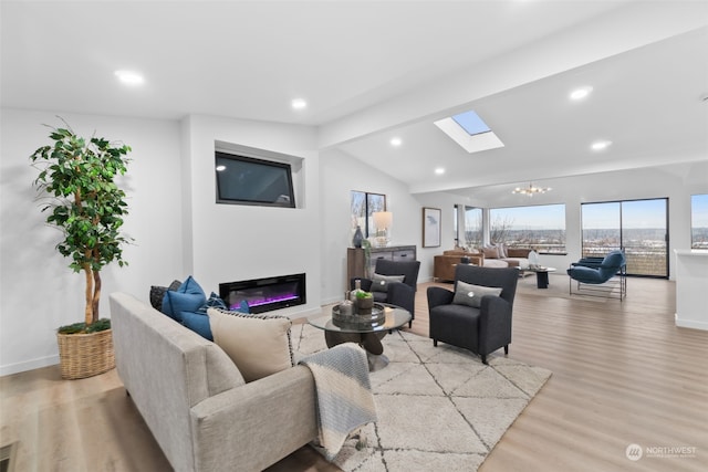 living room featuring vaulted ceiling with skylight, a notable chandelier, and light hardwood / wood-style floors