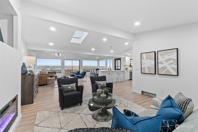 living room with a skylight, light wood-type flooring, and a chandelier