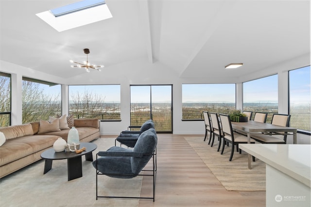 living room featuring light hardwood / wood-style floors, lofted ceiling with skylight, a healthy amount of sunlight, and a notable chandelier