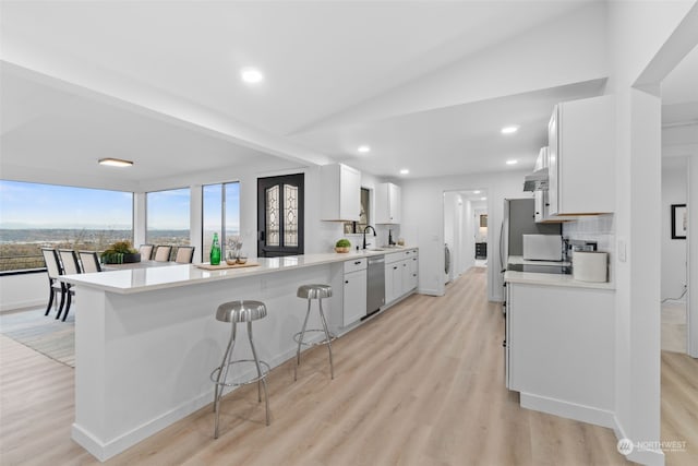 kitchen with white cabinets, appliances with stainless steel finishes, a breakfast bar, and kitchen peninsula