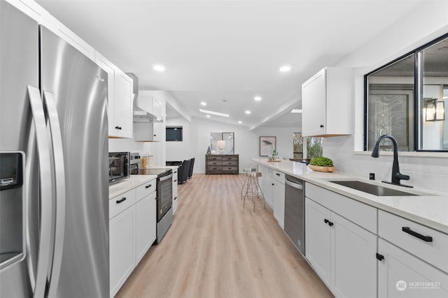 kitchen with white cabinets, stainless steel appliances, vaulted ceiling, and sink