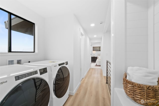 clothes washing area with separate washer and dryer and light hardwood / wood-style floors