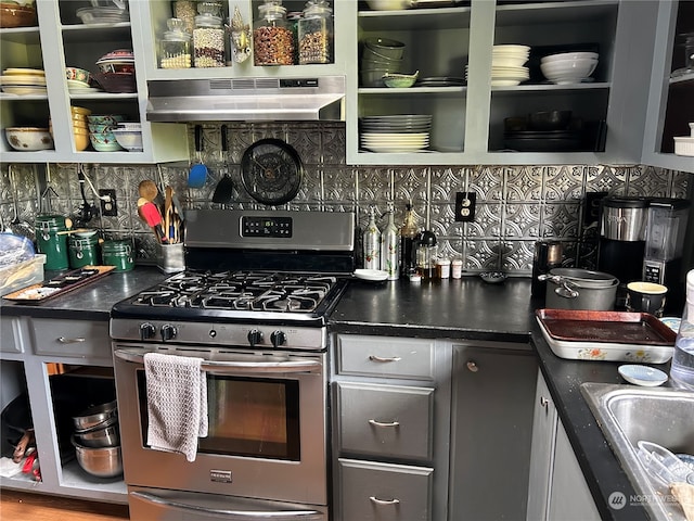 kitchen featuring backsplash, extractor fan, stainless steel gas range oven, and sink