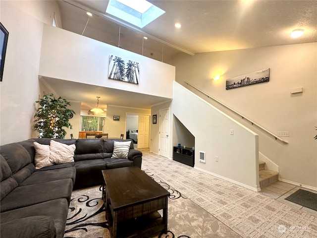 carpeted living room featuring a skylight and high vaulted ceiling