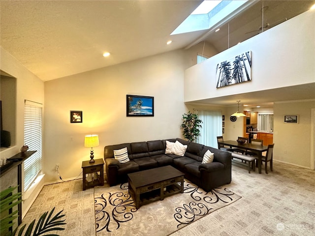 carpeted living room featuring a skylight and high vaulted ceiling