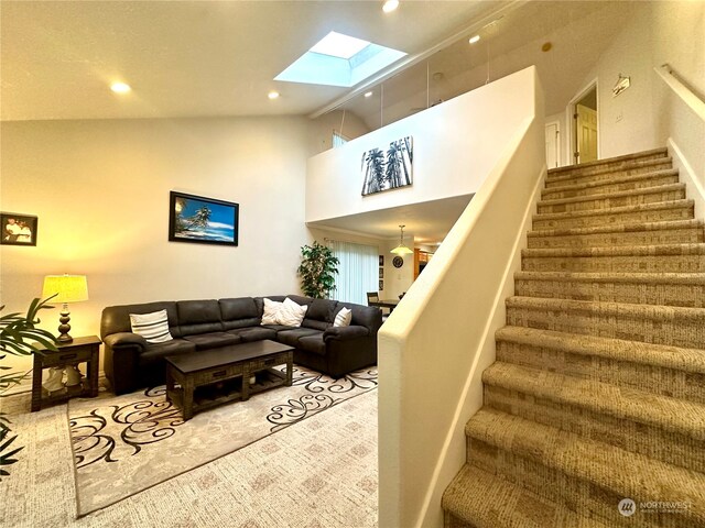 living room featuring carpet, high vaulted ceiling, and a skylight