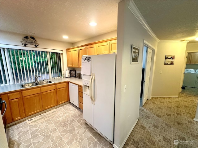 kitchen with white appliances, crown molding, sink, washer and dryer, and a textured ceiling