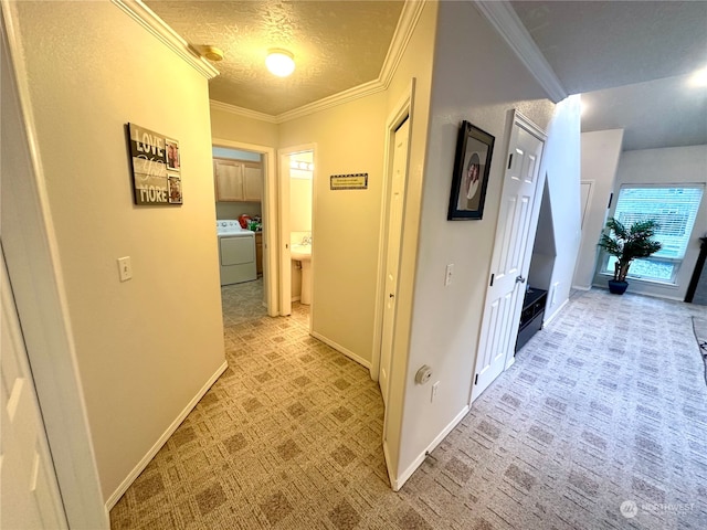 corridor with washer / dryer, a textured ceiling, light colored carpet, and crown molding