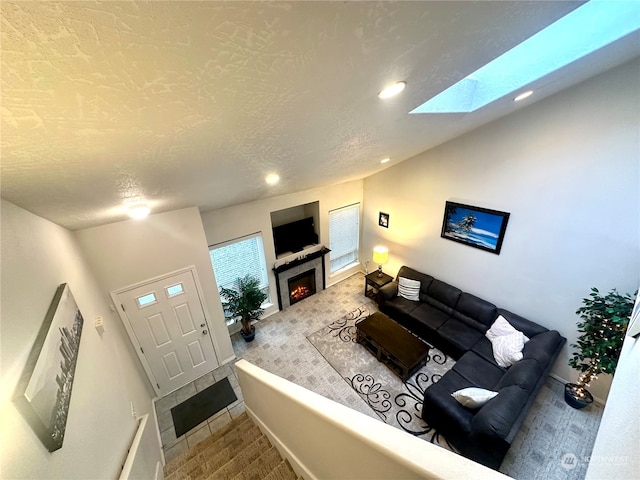 living room with carpet flooring, vaulted ceiling with skylight, and a textured ceiling