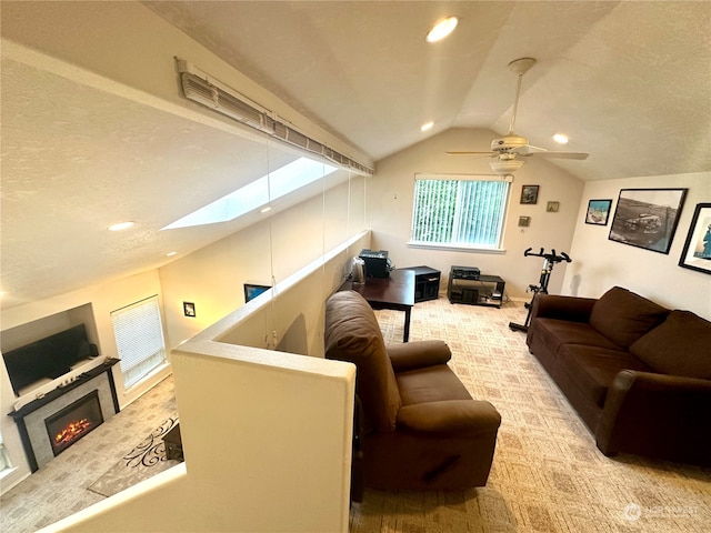 carpeted living room with ceiling fan, vaulted ceiling with skylight, and a textured ceiling