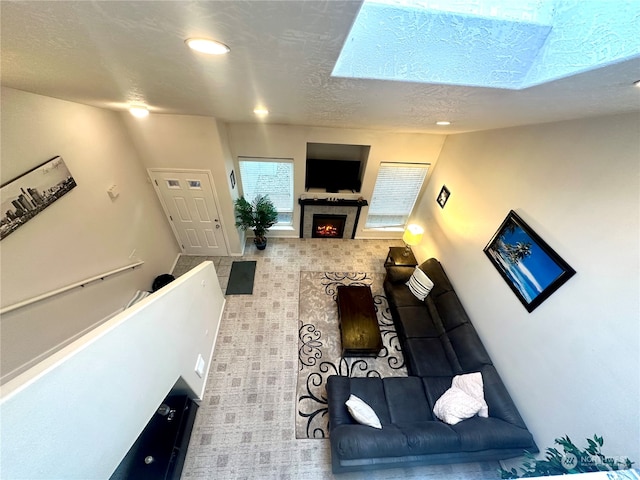 living room featuring a tile fireplace and a skylight