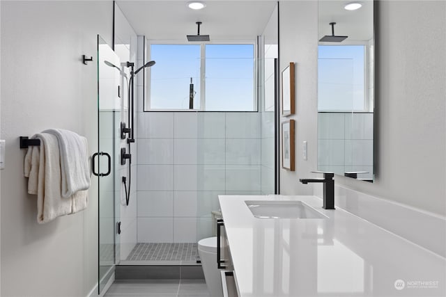 bathroom with tile patterned flooring, a shower with door, vanity, and toilet