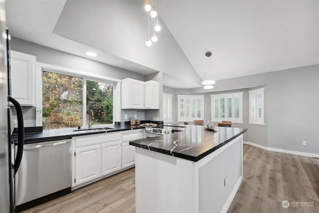 kitchen featuring sink, vaulted ceiling, decorative light fixtures, white cabinets, and appliances with stainless steel finishes