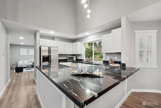 kitchen featuring kitchen peninsula, white cabinetry, light hardwood / wood-style flooring, and appliances with stainless steel finishes