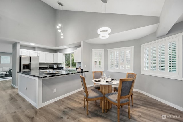 kitchen with kitchen peninsula, hardwood / wood-style floors, decorative light fixtures, white cabinets, and appliances with stainless steel finishes