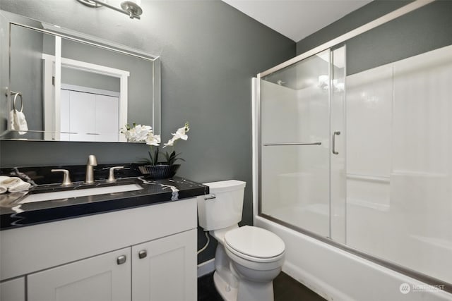 full bathroom with combined bath / shower with glass door, vanity, and toilet