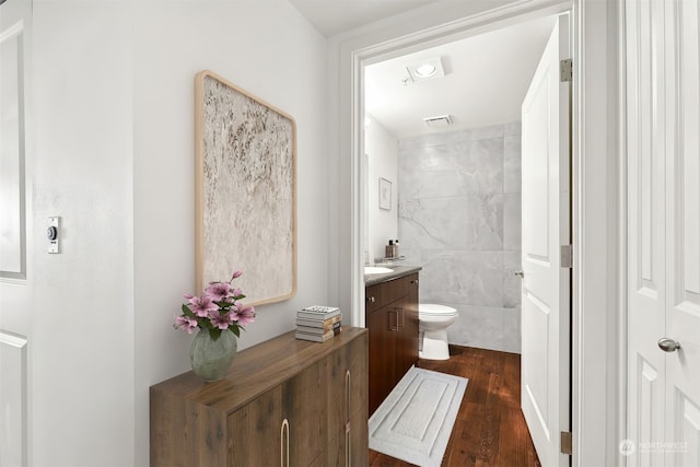 bathroom with vanity, toilet, wood-type flooring, and tile walls