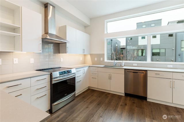 kitchen featuring sink, dark wood-type flooring, wall chimney range hood, white cabinets, and appliances with stainless steel finishes