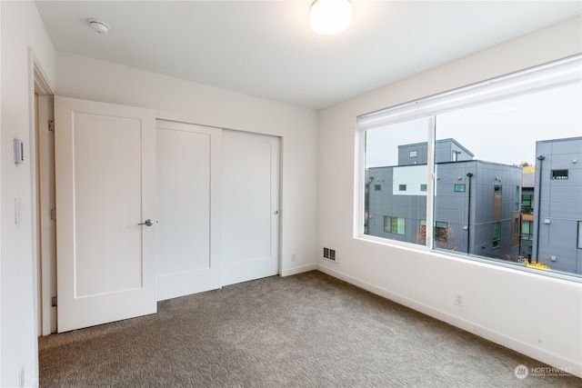 unfurnished bedroom featuring dark carpet and a closet