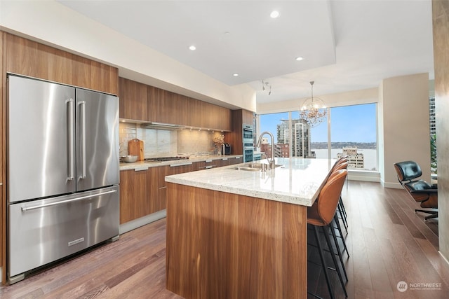 1920 4th Ave Unit 1802, Seattle, WA 98101 - kitchen featuring appliances with stainless steel finishes, brown cabinetry, modern cabinets, dark wood finished floors, and recessed lighting