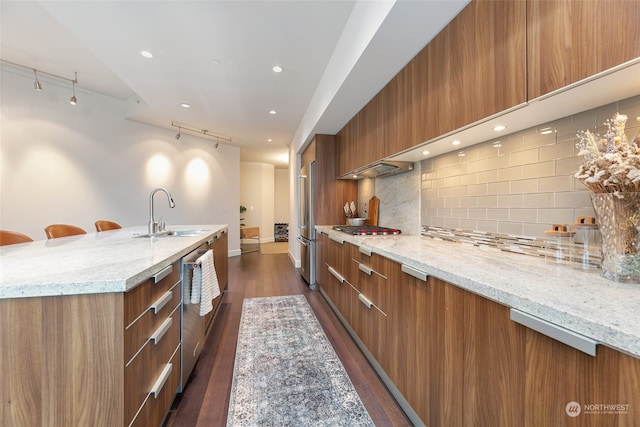 kitchen with sink, light stone countertops, appliances with stainless steel finishes, tasteful backsplash, and dark hardwood / wood-style flooring