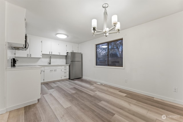 kitchen featuring hanging light fixtures, a notable chandelier, light hardwood / wood-style floors, white cabinetry, and stainless steel refrigerator