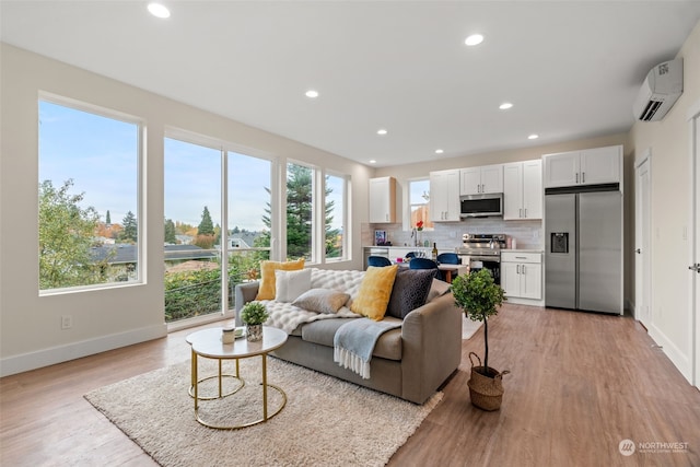 living room with light hardwood / wood-style flooring, a wall unit AC, a healthy amount of sunlight, and sink