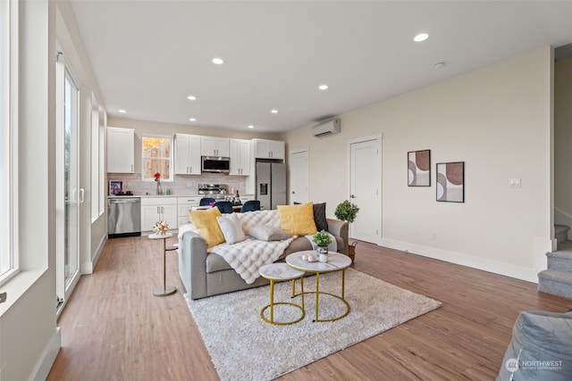 living room featuring light hardwood / wood-style flooring, a wall mounted air conditioner, and sink