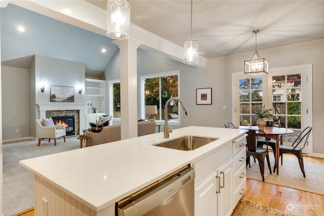 kitchen featuring pendant lighting, dishwasher, a center island with sink, sink, and a fireplace