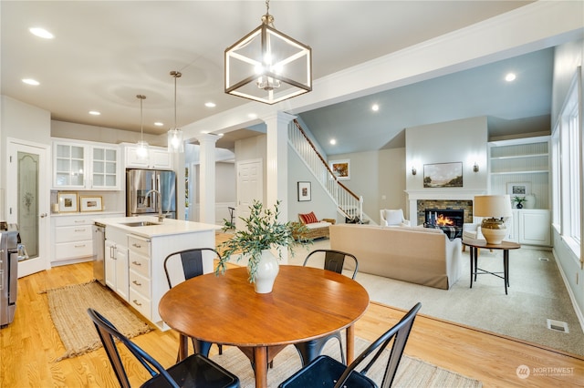 dining area with a fireplace, light hardwood / wood-style flooring, an inviting chandelier, and sink