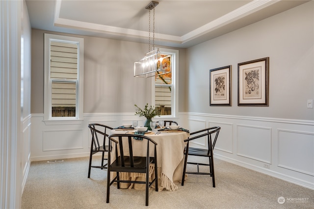 carpeted dining space featuring a raised ceiling and a chandelier