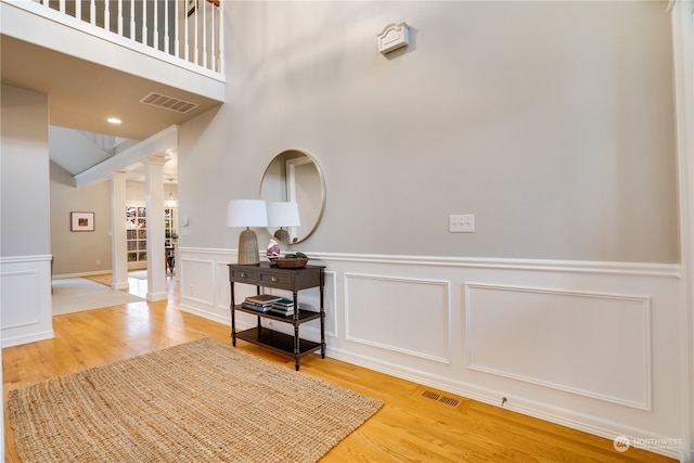 entrance foyer with a high ceiling, hardwood / wood-style flooring, and ornate columns