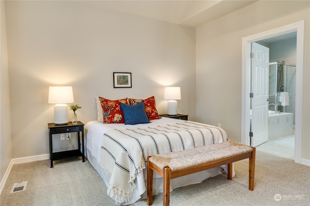 bedroom featuring ensuite bathroom and light carpet