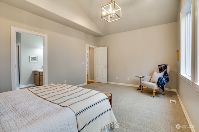 bedroom with a chandelier, lofted ceiling, light carpet, and ensuite bath