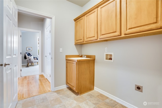 laundry area featuring electric dryer hookup, cabinets, sink, hookup for a washing machine, and light hardwood / wood-style floors