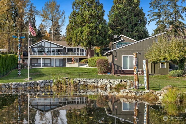 rear view of house with a lawn, a sunroom, and a water view