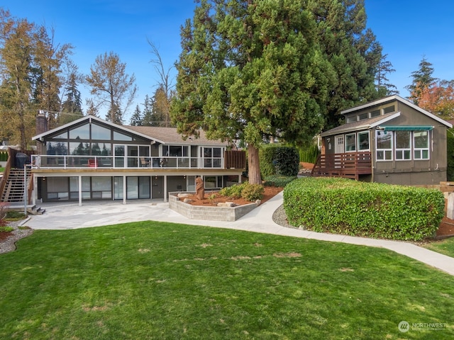 back of house featuring a lawn, a sunroom, a patio, and a deck